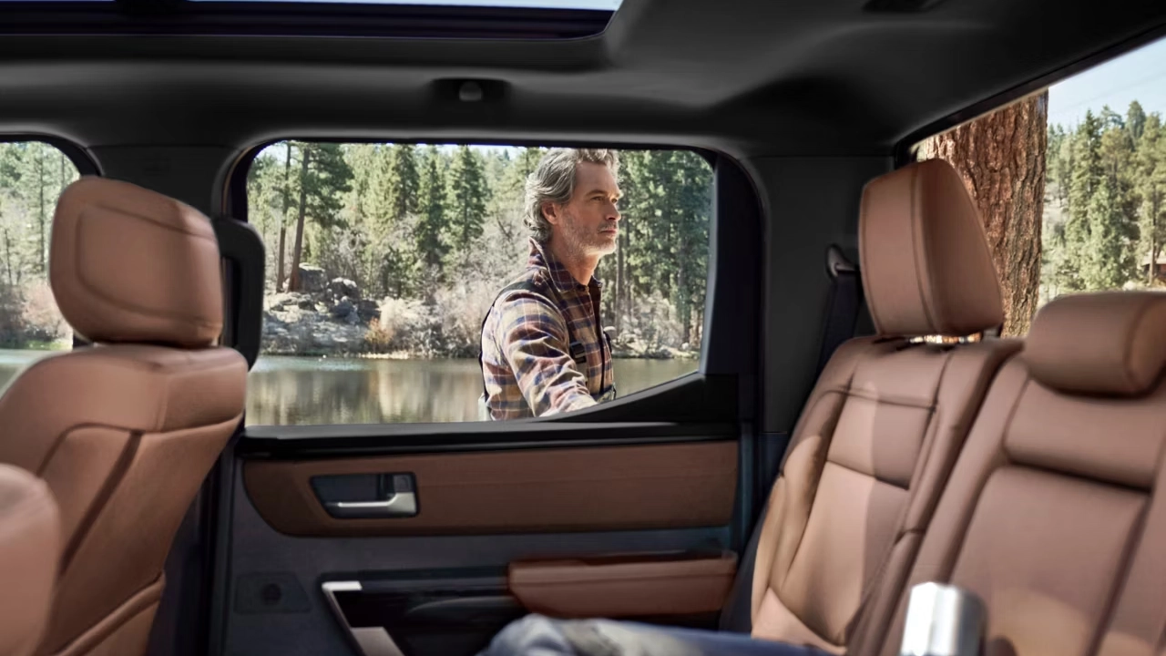 Toyota Tundra interior with brown leather seats and a man admiring a forest landscape