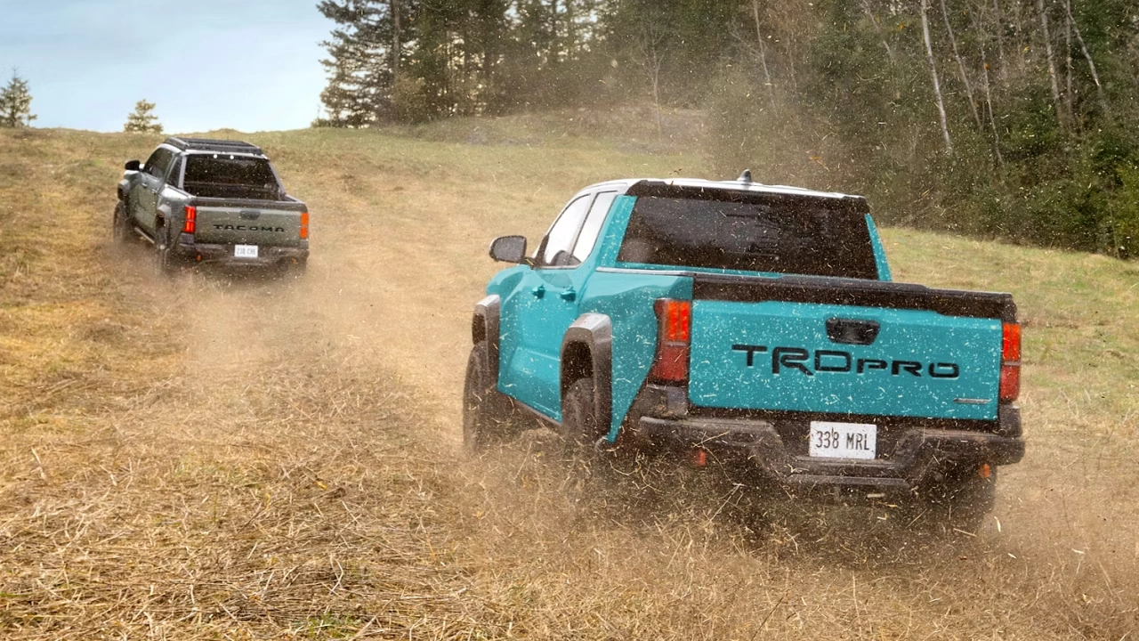 Two 2026 Toyota Tacoma TRDs driving off-road on a dusty dirt road