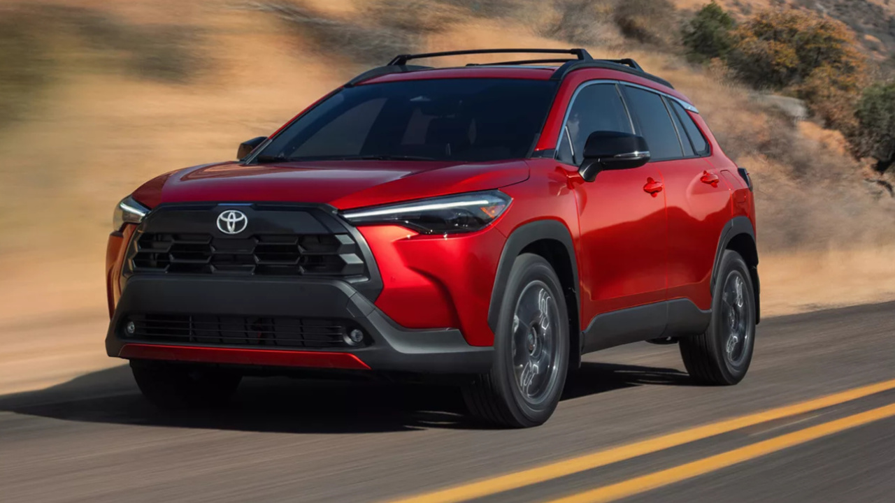 Toyota Corolla Cross hybride 2026 rouge vu de trois quarts avant sur une route.