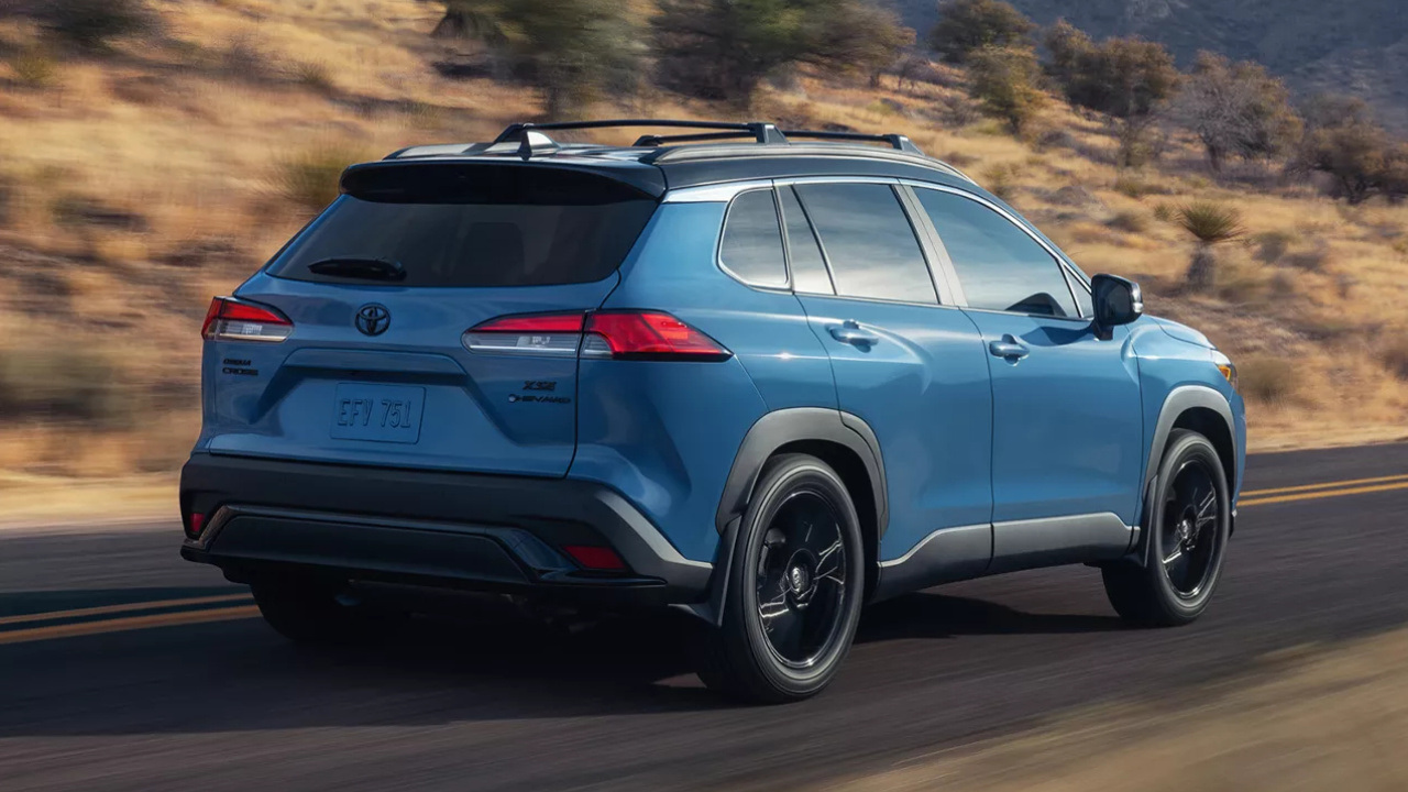 Toyota Corolla Cross hybride 2026 bleu vu de trois quarts arrière sur la route.