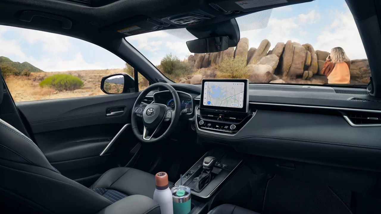 Habitacle du Toyota Corolla Cross hybride 2026 avec volant, écran central et console avant.