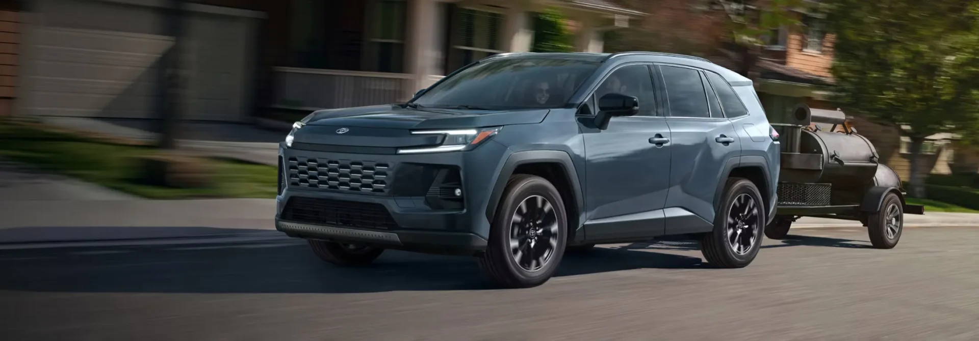 Toyota RAV4 2026 bleu remorquant une petite embarcation sur la route.